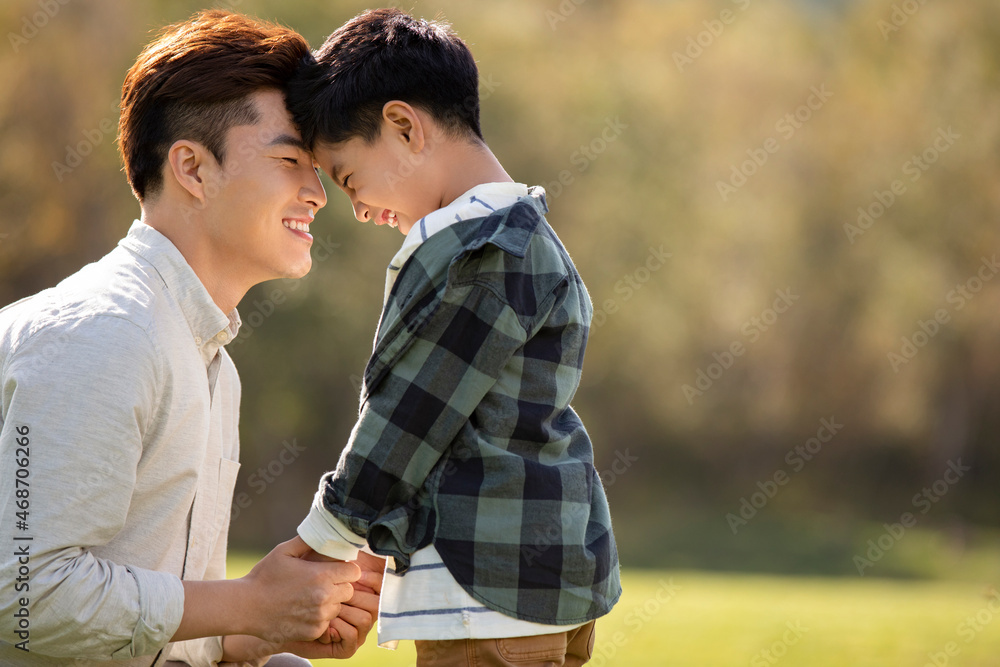 Happy Chinese father and son playing on meadow
