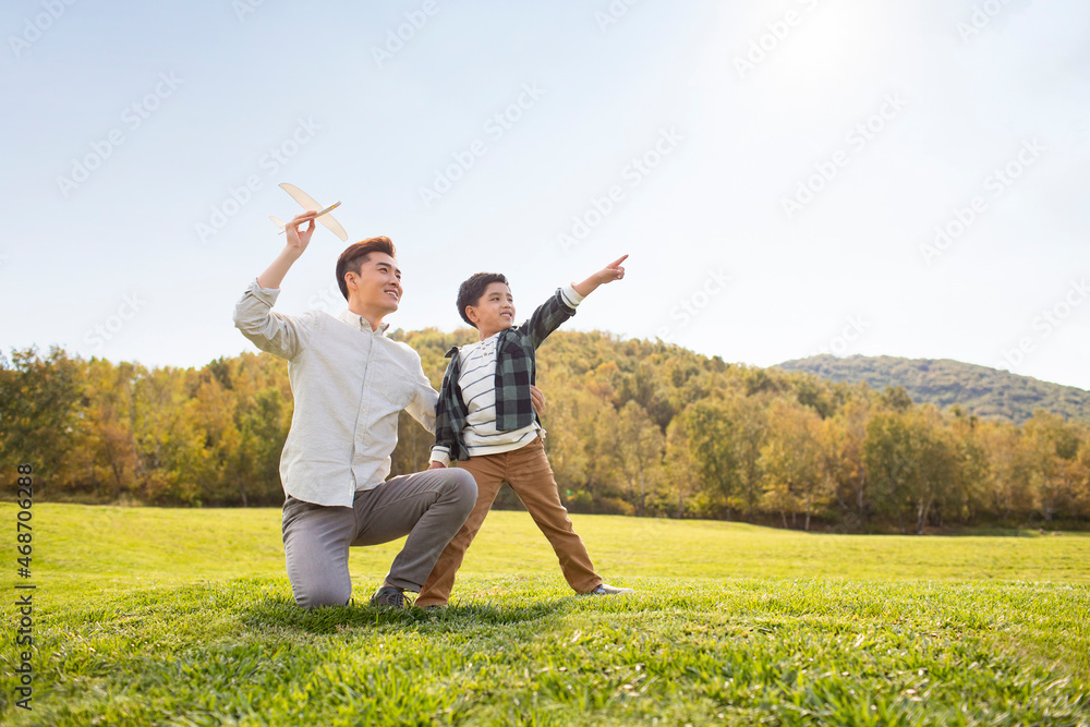 Happy Chinese father and son playing on meadow Happy Chinese father and son playing on meadow