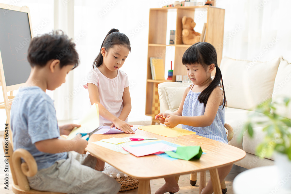 Cute Chinese children doing paper craft in living room Cute Chinese children doing paper craft in living room