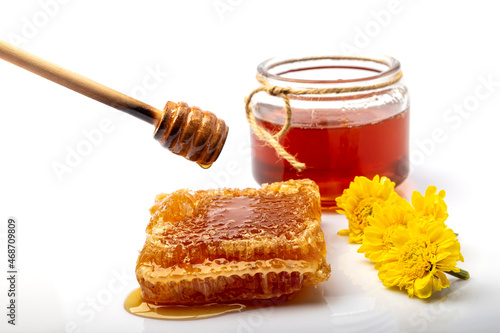 Honeycomb with honey, honey in a jar, honey dipper, yellow gerbera isolated on white background.