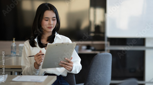 Portrait of successful young Asian businesswoman working with financial report at her office