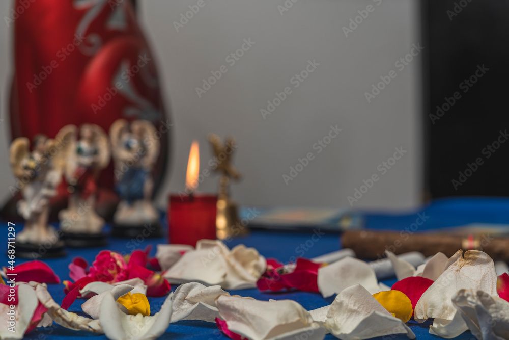 white and red petals on the table, three blurred angels figurines in the background