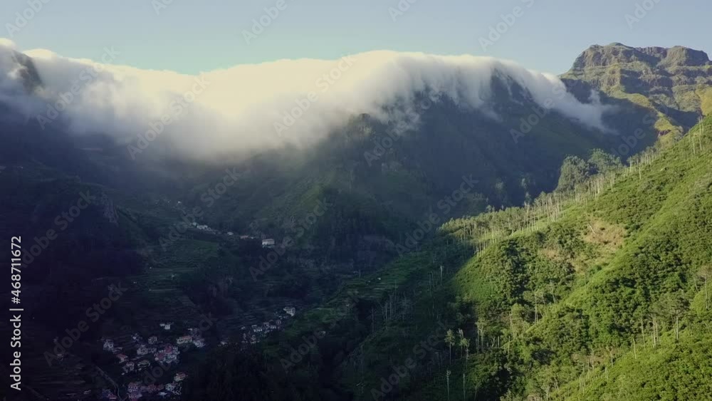 Aerial view moving away from clouds falling over ridge in tropical mountains Aerial view moving away from clouds falling over ridge in tropical mountains
