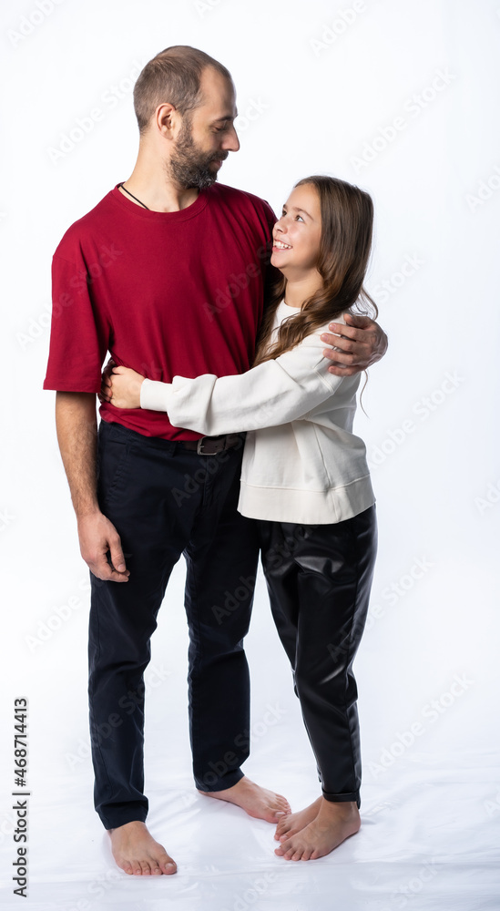dad hugs daughter by the shoulders in the studio. a man in a burgundy-red T-shirt, a girl in a white sweatshirt. isolated white background dad hugs daughter by the shoulders in the studio. a man in a burgundy-red T-shirt, a girl in a white sweatshirt. isolated white background