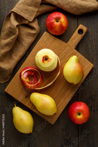 Peeled red apples and pears on wooden cutting board. Food background vertical