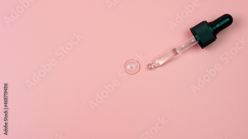 Dropper with cosmetic gel on a pink background.