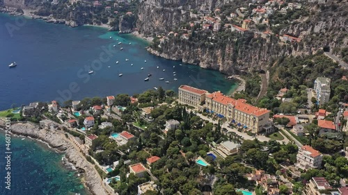 Cap d'Ail France Aerial v5 cinematic birds eye view capturing hillside resorts toward rocky cliffside mala beach with sailboats and yachts - July 2021 photo