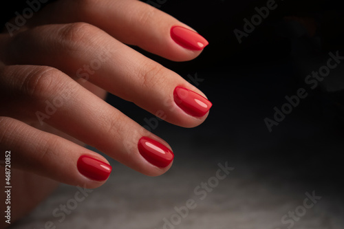 Beautiful manicure on a woman's hand. Red nails on a dark background. Nail design.