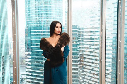 Gorgeous woman in coat standing in modern apartaments photo