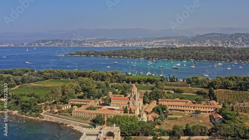 Cannes France Aerial v22 cinematic dolly in shot, drone flying over island of saint honorat and the cistercian abbey overlooking at sailboats cruising on mediterranean sea during summer - July 2021 photo