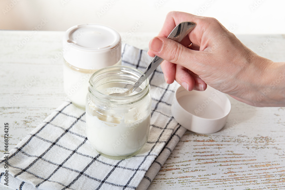 A woman's hand tastes freshly made yogurt with a spoon. A woman's hand tastes freshly made yogurt with a spoon.