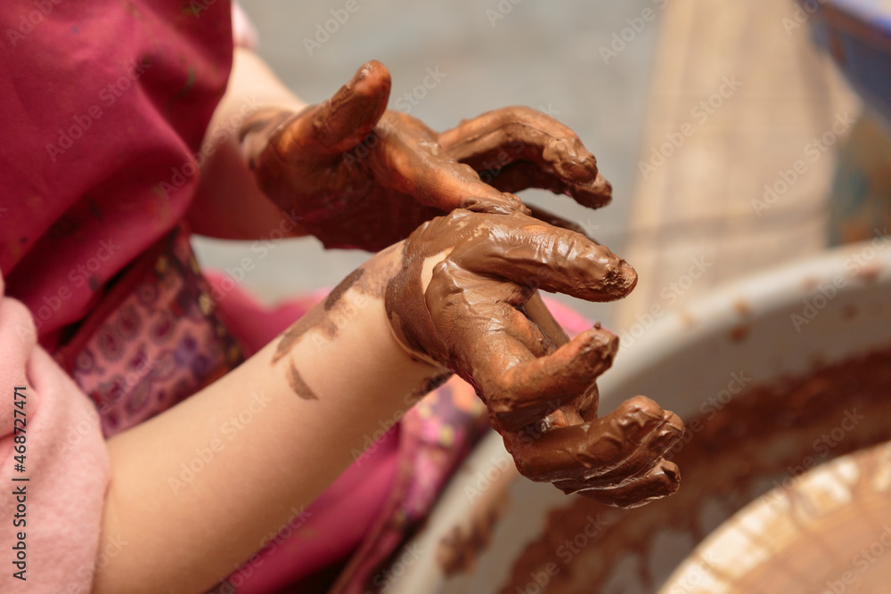 Children's hands are smeared by clay.