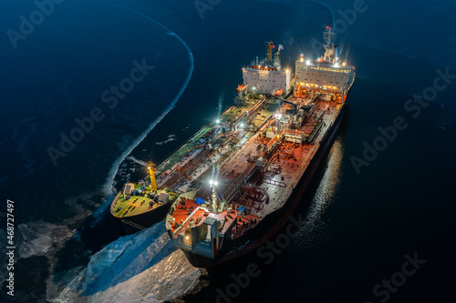 Two tankers at night, stand nearby in young ice. Shooting from air.