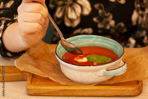 A woman is eating tomato soup
