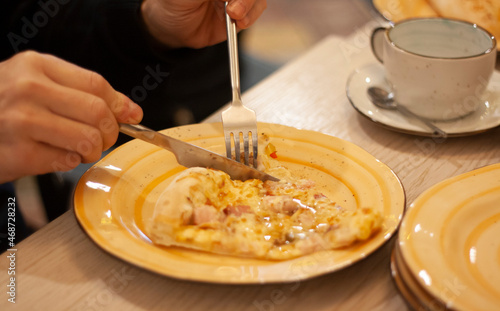 A man eats pizza with a knife and fork