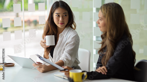 Businesswoman is listening to one of her coworkers explain project.