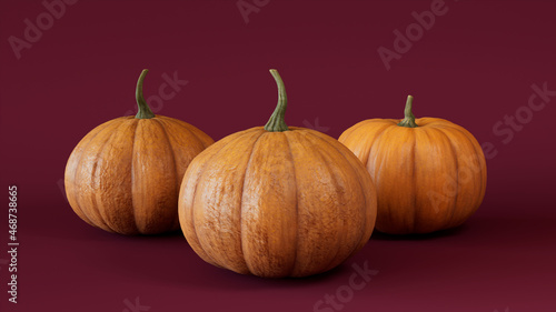 Three Pumpkins on a Burgundy colored background. Autumn themed Image.