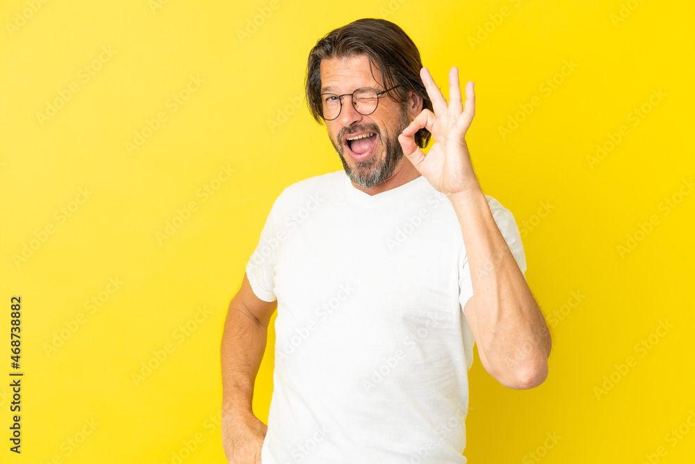 Senior dutch man isolated on yellow background showing ok sign with fingers Senior dutch man isolated on yellow background showing ok sign with fingers