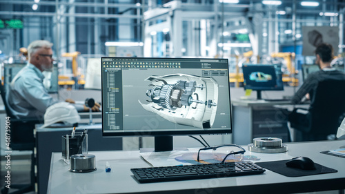 Car Factory Office: On the Desk Computer with Turbine Prototype, Design Advanced 3D Model for High-Tech Green Energy Electric Engine. Automated Robot Arm Assembly Line Manufacturing Facility