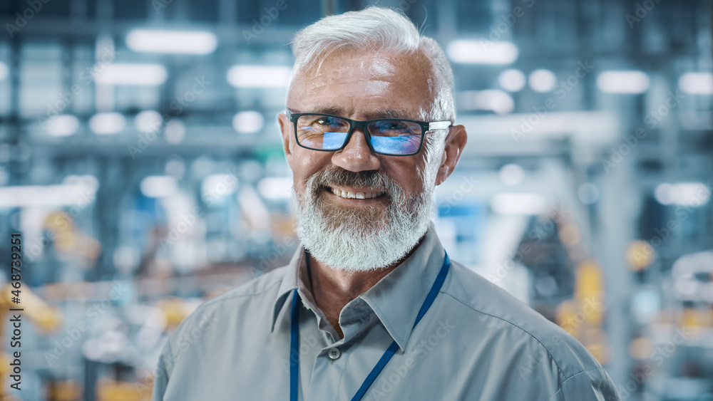 Car Factory Office: Portrait of Senior White Male Chief Engineer Looking at Camera and Smiling. Professional Technician in Automated Robot Arm Assembly Line Manufacturing in High-Tech Facility Car Factory Office: Portrait of Senior White Male Chief Engineer Looking at Camera and Smiling. Professional Technician in Automated Robot Arm Assembly Line Manufacturing in High-Tech Facility