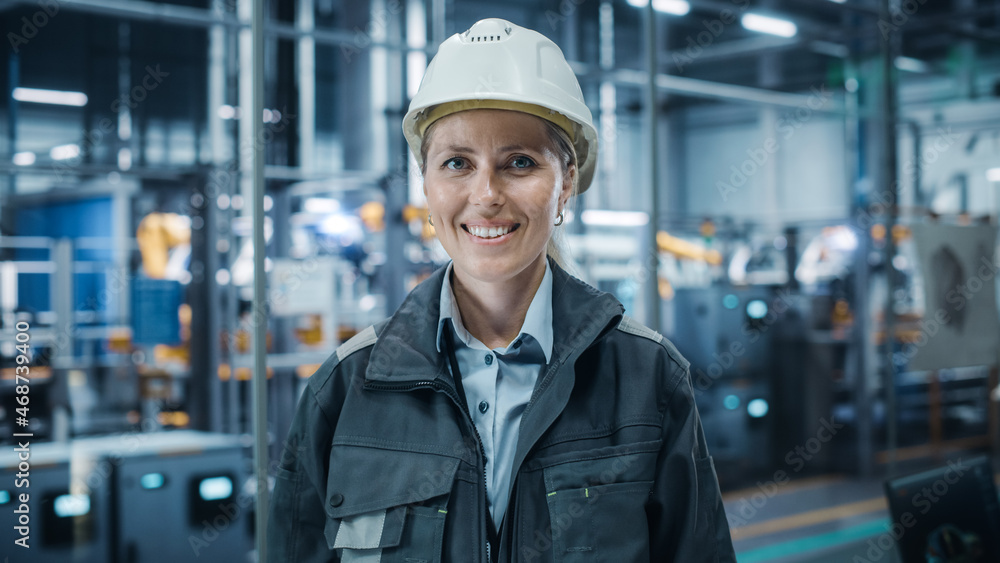 Car Factory Office: Portrait of Female Chief Engineer Wearing Hard Hat Looking at Camera, Smiling. Professional Technician. Automated Robot Arm Assembly Line Manufacturing High-Tech Electric Vehicles Car Factory Office: Portrait of Female Chief Engineer Wearing Hard Hat Looking at Camera, Smiling. Professional Technician. Automated Robot Arm Assembly Line Manufacturing High-Tech Electric Vehicles