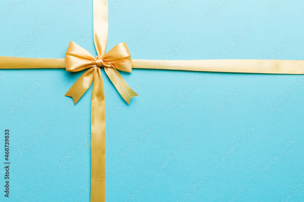 Top view of gold ribbon rolled and yellowbow isolated on colored background. Flat lay with copy space Top view of gold ribbon rolled and yellowbow isolated on colored background. Flat lay with copy space