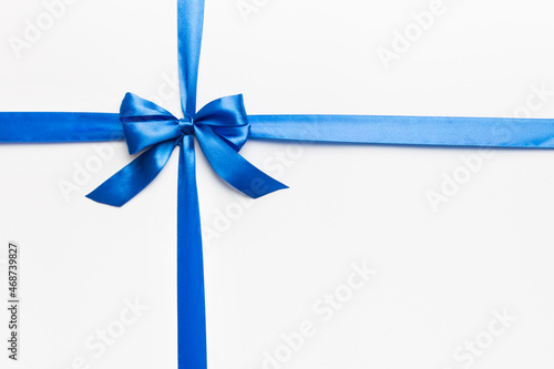 Top view of blue ribbon rolled and blue bow isolated on colored background. Flat lay with copy space