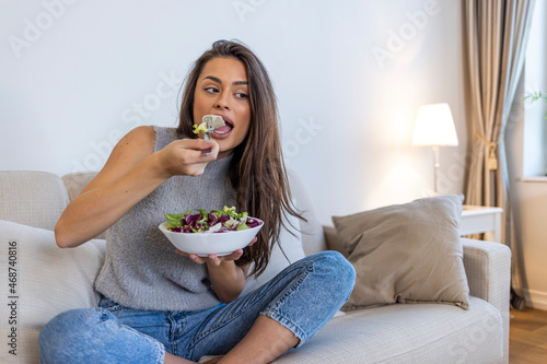 Beautiful healthy woman eating salad  Dieting Concept. Healthy Lifestyle.  Woman eating fresh salad in a bowl at home with a happy face standing and smiling with a confident smile
