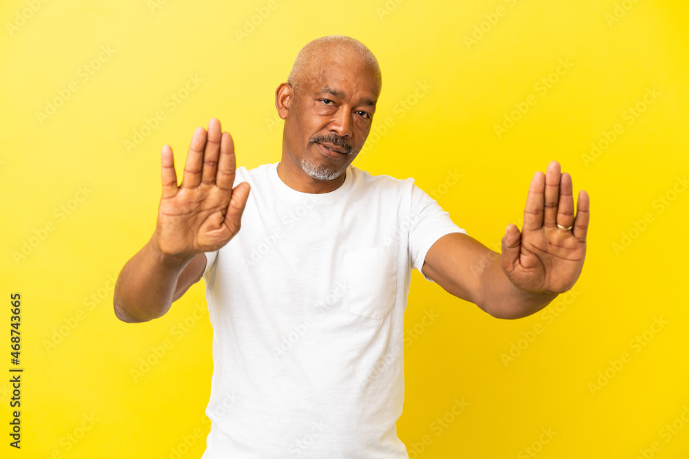 Cuban Senior isolated on yellow background making stop gesture and disappointed Cuban Senior isolated on yellow background making stop gesture and disappointed