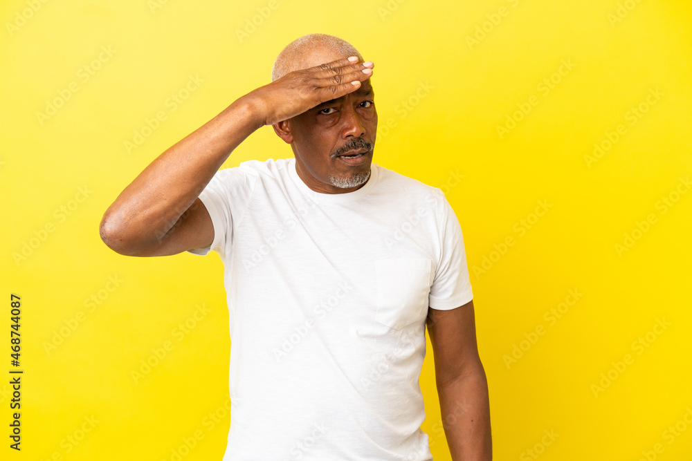 Cuban Senior isolated on yellow background doing surprise gesture while looking to the side Cuban Senior isolated on yellow background doing surprise gesture while looking to the side