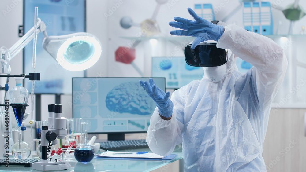 Fototapeta premium Scientist researcher wearing virtual reality headset analyzing brain activity futuristic holografic interface during chemistry experiment in biochemistry hospital laboratory. Neuroscience research