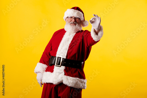 Santa Claus making the OK gesture on yellow background