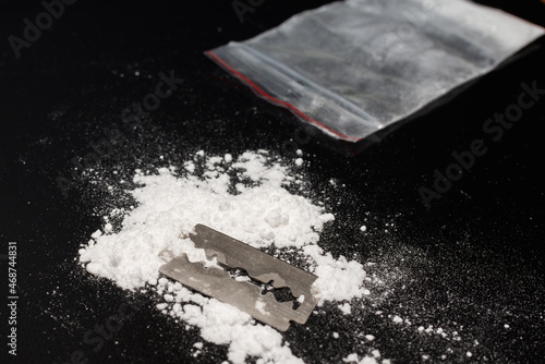 Razor Blade on drug powder,cocaine bag on reflection black background.Copy space. photo