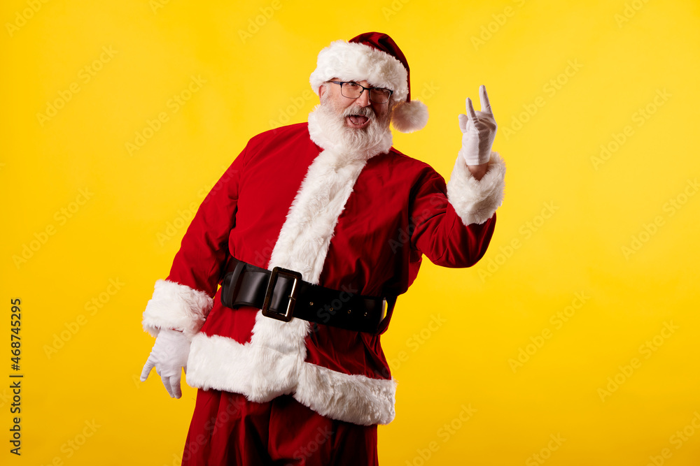 Santa Claus making a rocker gesture on yellow background