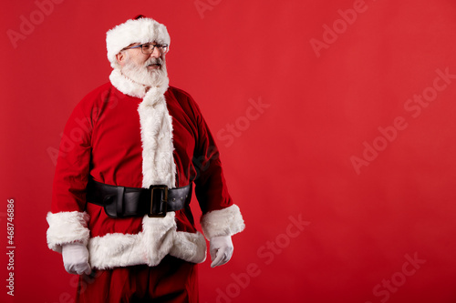 Santa Claus pointing his eyes at a poster on a red background