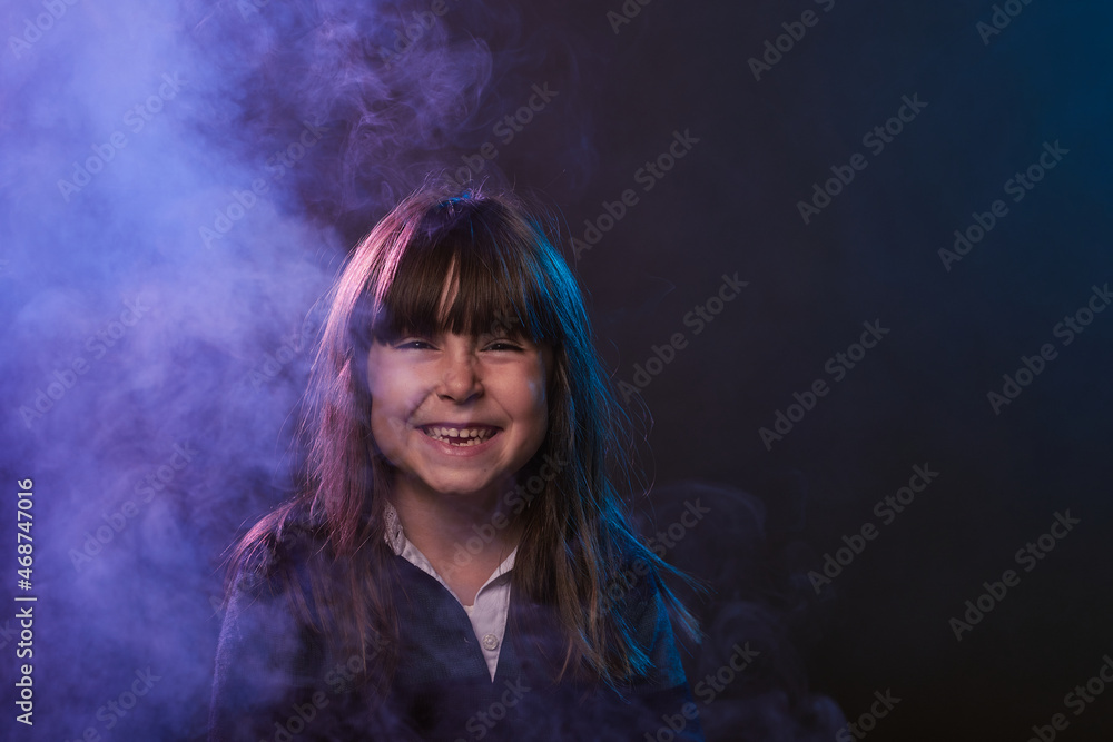 portrait with copy space of a 5-year-old girl having fun with smoke and colored lights