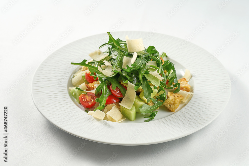 Panzanella salad with vegetables, rucola, parmesan and bread in a white plate
