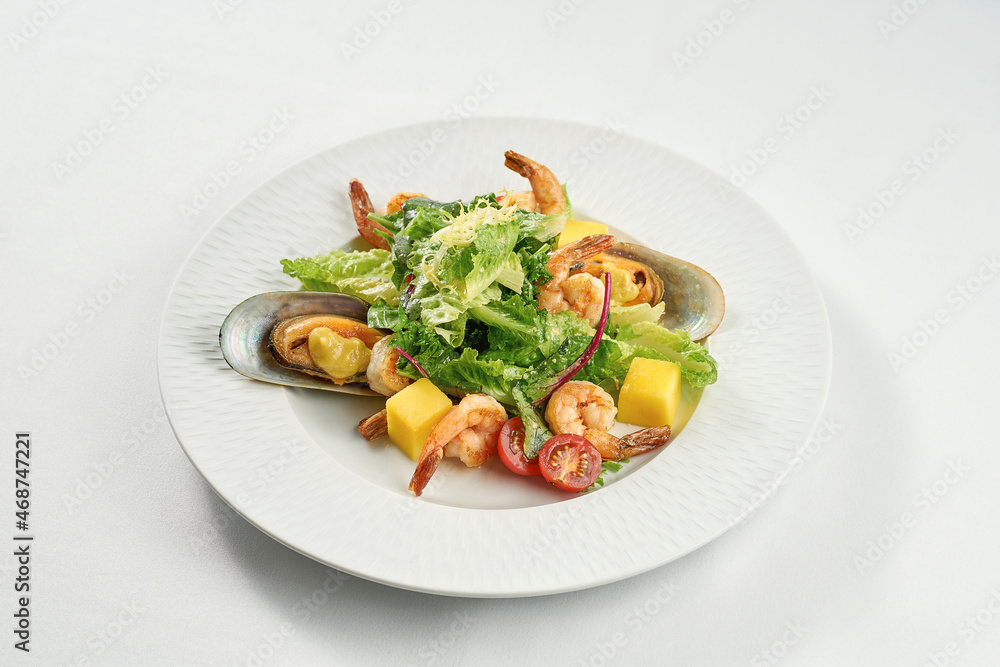 Shrimp and mussel salad, mango in a white plate on a tablecloth Shrimp and mussel salad, mango in a white plate on a tablecloth