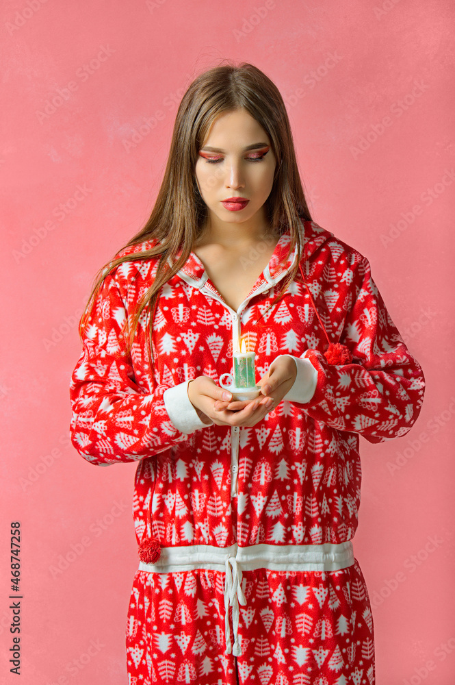 New Year's portrait of a beautiful girl in red pajamas. pink background