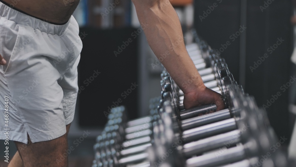 Arab man athlete is grabbing a dumbbell from a big selection in a fitness center. Arab man athlete is grabbing a dumbbell from a big selection in a fitness center.