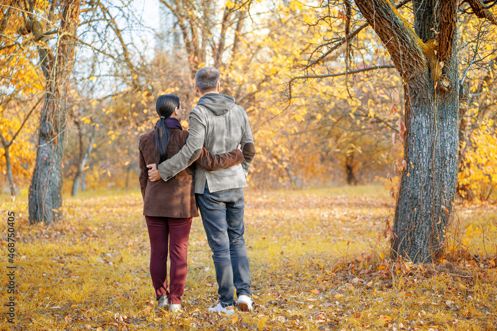 Nice Pair Admires the Amazing Fall Nature Around. Couple Enjoying One Another And the Good Weather Outside. Standing Back to Camera. Autumn Background. Full-length Nice Pair Admires the Amazing Fall Nature Around. Couple Enjoying One Another And the Good Weather Outside. Standing Back to Camera. Autumn Background. Full-length