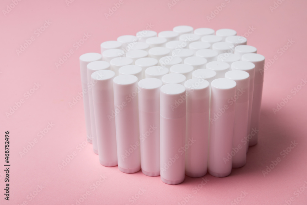 Lot of white plastic lip gloss tubes on pink background Lot of white plastic lip gloss tubes on pink background