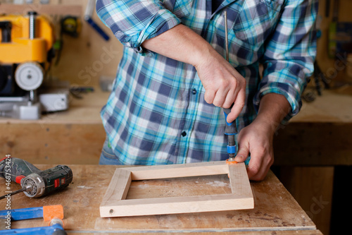Cuadro en lienzo A carpenter in a plaid shirt works a workshop