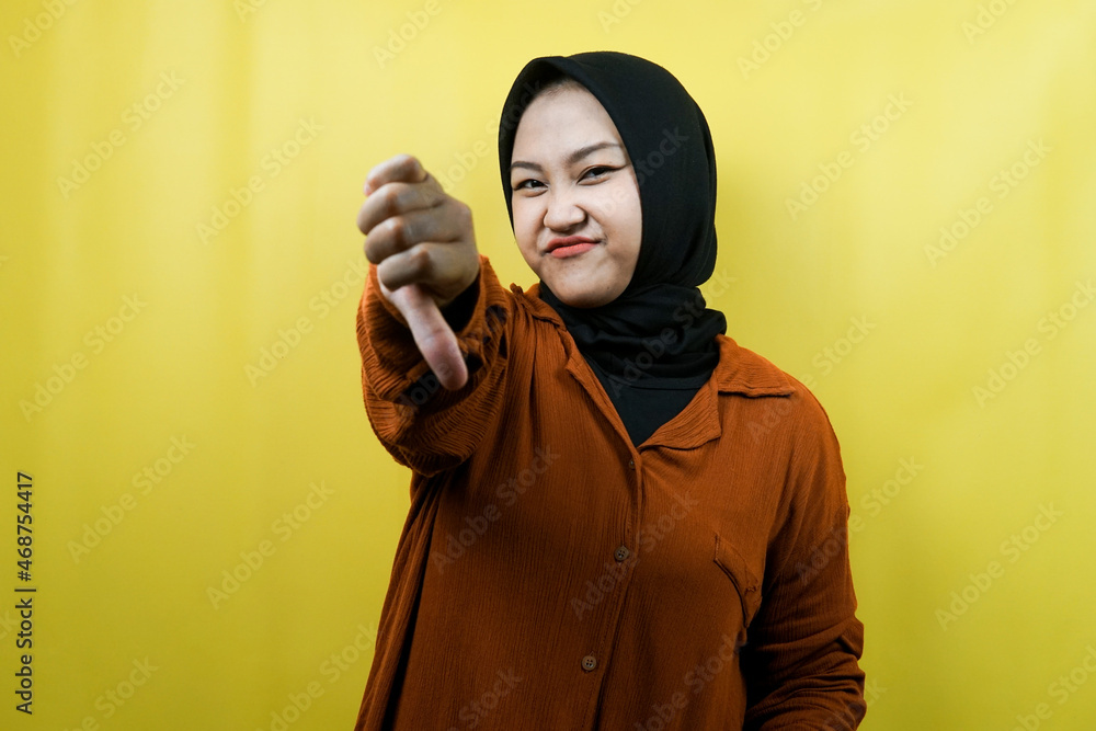 Beautiful young asian muslim woman with dislike hand, bad, looking at camera isolated Beautiful young asian muslim woman with dislike hand, bad, looking at camera isolated