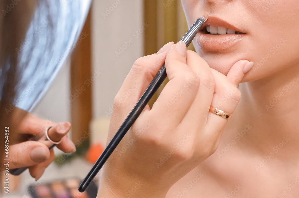 Applying makeup for a beautiful woman. The makeup artist works in his studio. Lipstick. Close-up. selective focus Applying makeup for a beautiful woman. The makeup artist works in his studio. Lipstick. Close-up. selective focus