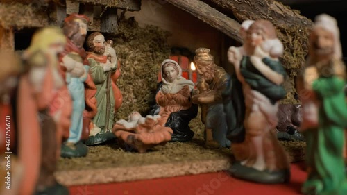 Christmas manger nativity scene with figures and atmospheric candles lights. Religious scene of christmas figurines