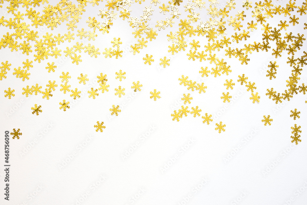 Golden confetti in the form of snowflakes on white background. Festive day backdrop. Flat lay style with minimalistic design. Template for banner or party invitation Golden confetti in the form of snowflakes on white background. Festive day backdrop. Flat lay style with minimalistic design. Template for banner or party invitation
