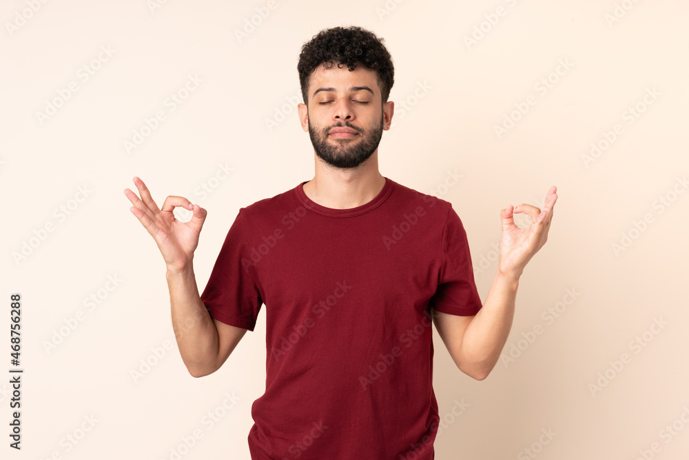 Young Moroccan man isolated on beige background in zen pose Young Moroccan man isolated on beige background in zen pose
