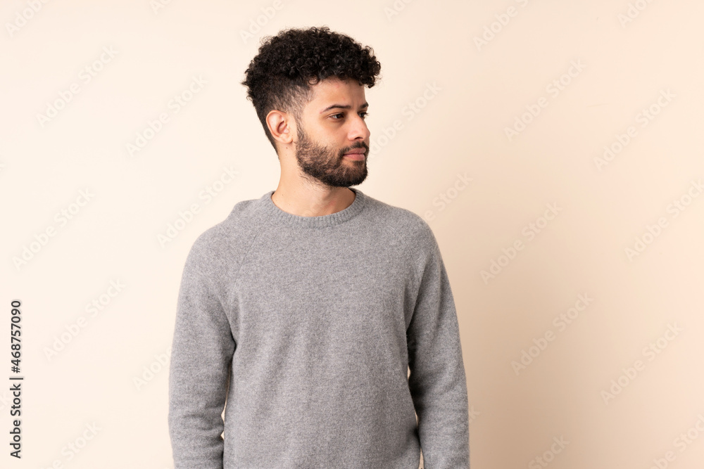Young Moroccan man isolated on beige background looking to the side Young Moroccan man isolated on beige background looking to the side