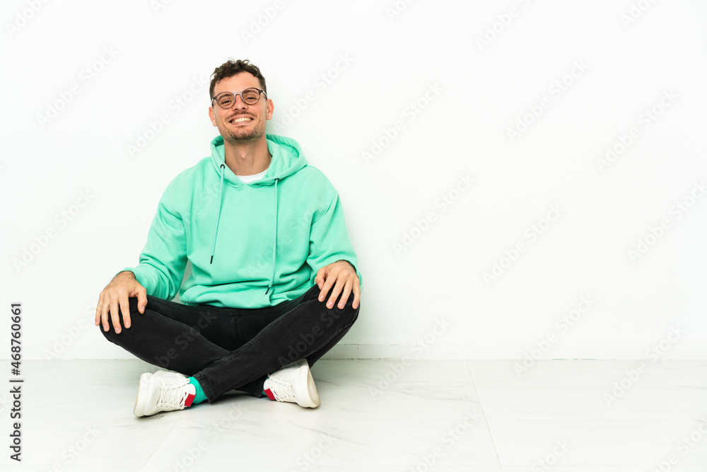 Young handsome caucasian man sitting on the floor with glasses and happy Young handsome caucasian man sitting on the floor with glasses and happy
